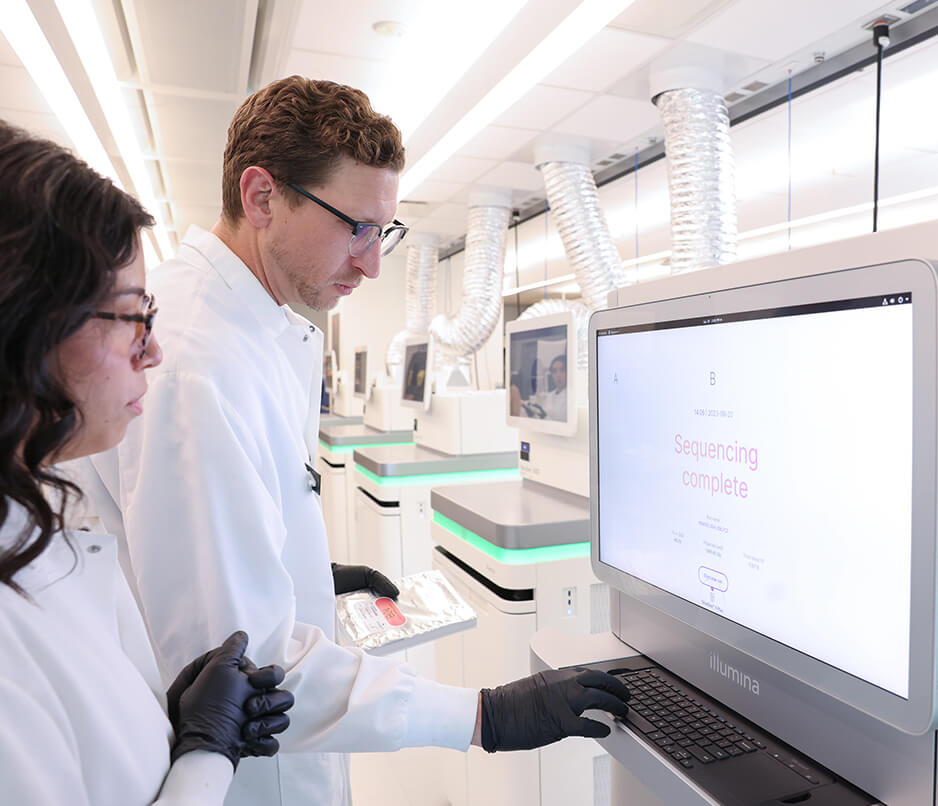 Two scientists view a screen that indicates sequencing complete